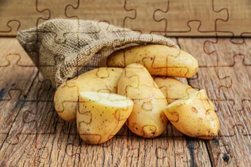 Raw organic potatoes in the sack on wood planks ba jigsaw puzzle